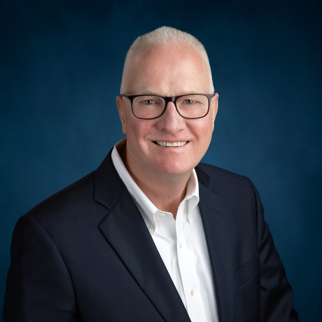 a man in a suit and glasses smiling at the camera