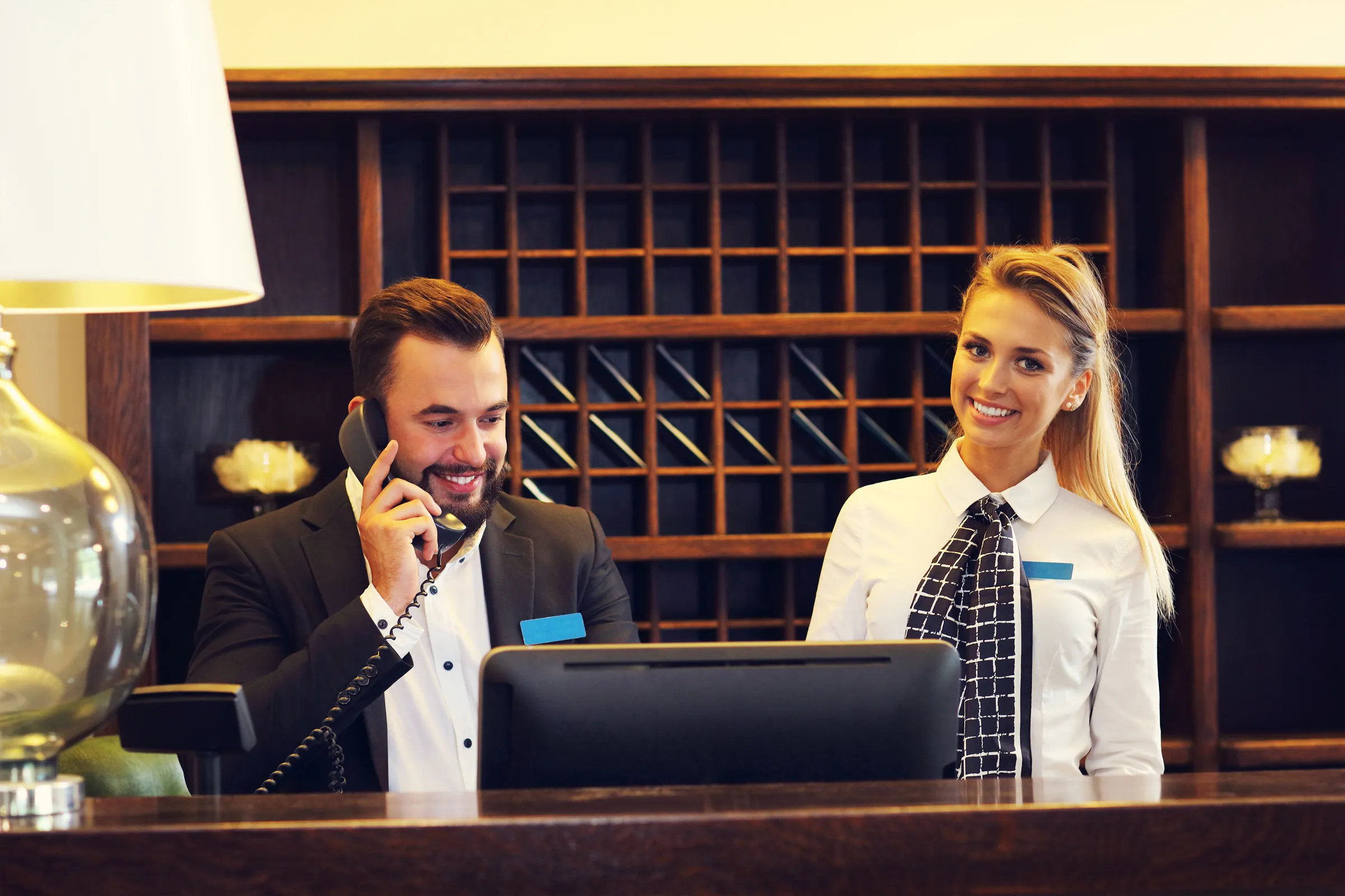 a man and woman sitting at a desk talking on the phone